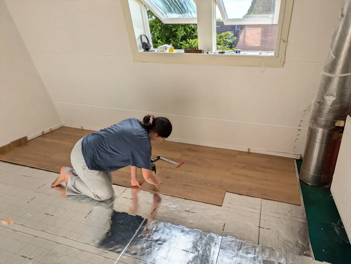 Sophia is on her knees, laying the floor.